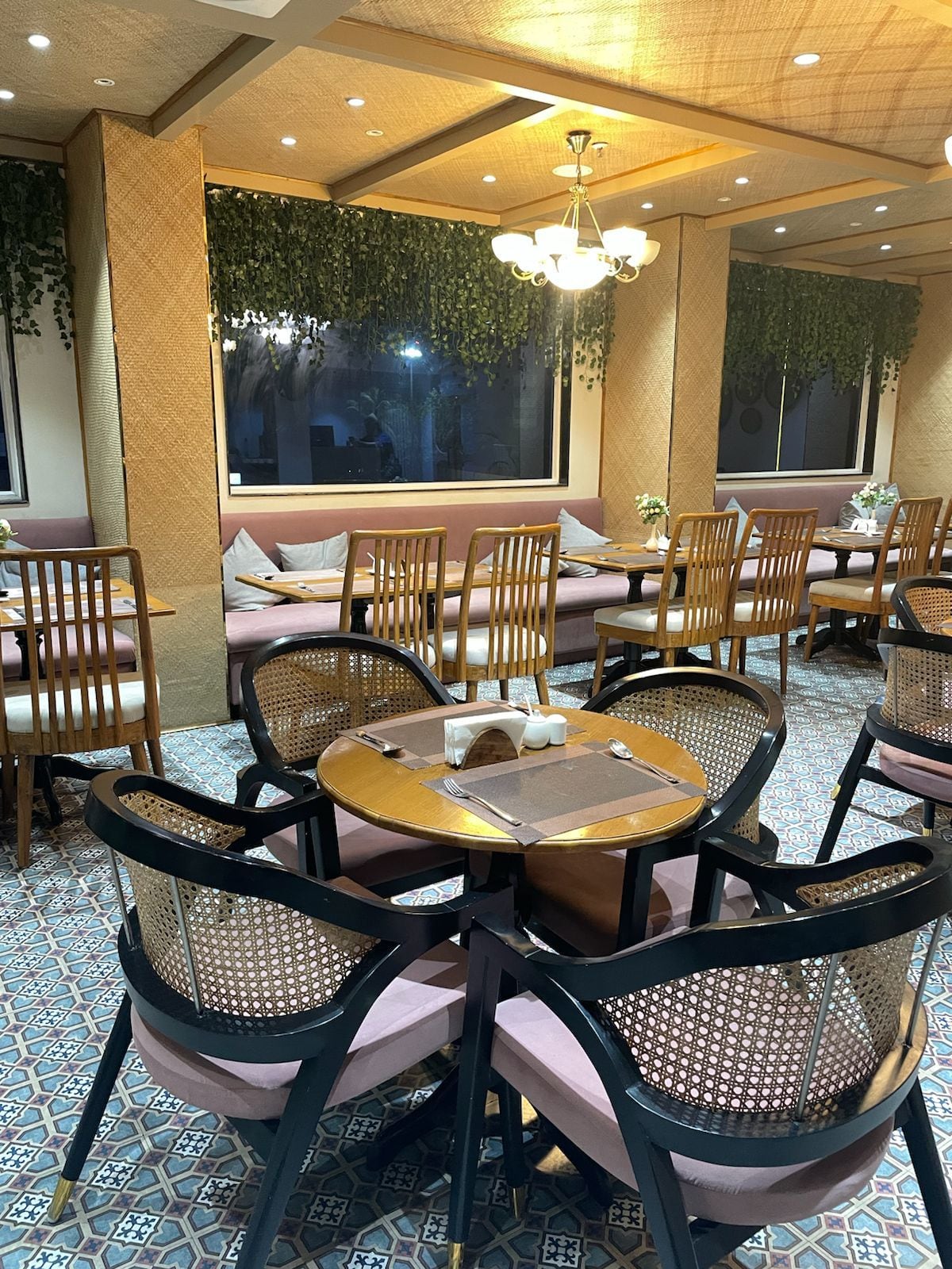 Sunlit dining room with arched windows, olive velvet chairs and hanging plants